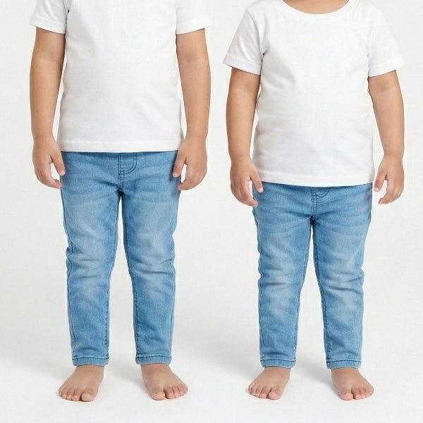 Two children wearing white t-shirts and blue jeans on a plain background